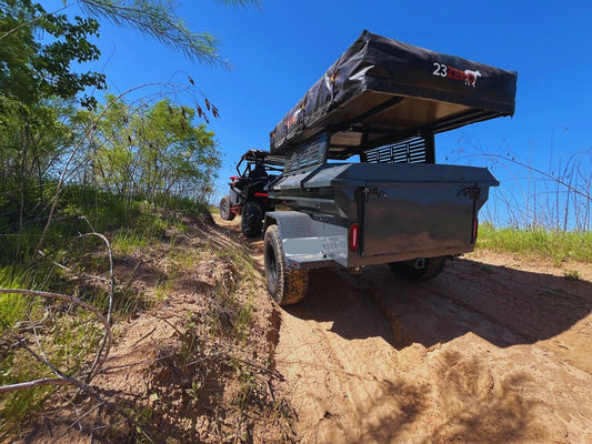 M416-style off-road overland trailer towed on a dirt trail